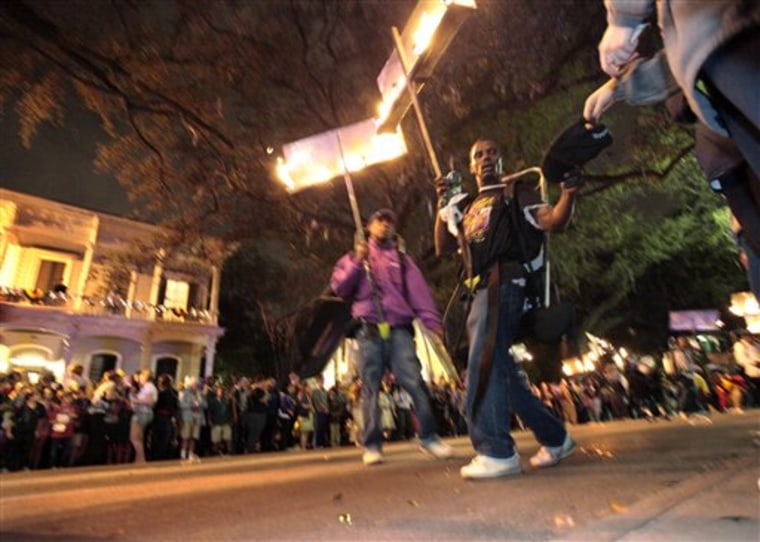 In this March 3, 2011 photo, a flambeau accepts a tip from a reveler during the Krewe of Chaos Mardi Gras parade on St. Charles Ave. in New Orleans. The crescent city expects its largest crowd for the annual celebration since Hurricane Katrina struck in 2005. (AP Photo/Gerald Herbert)